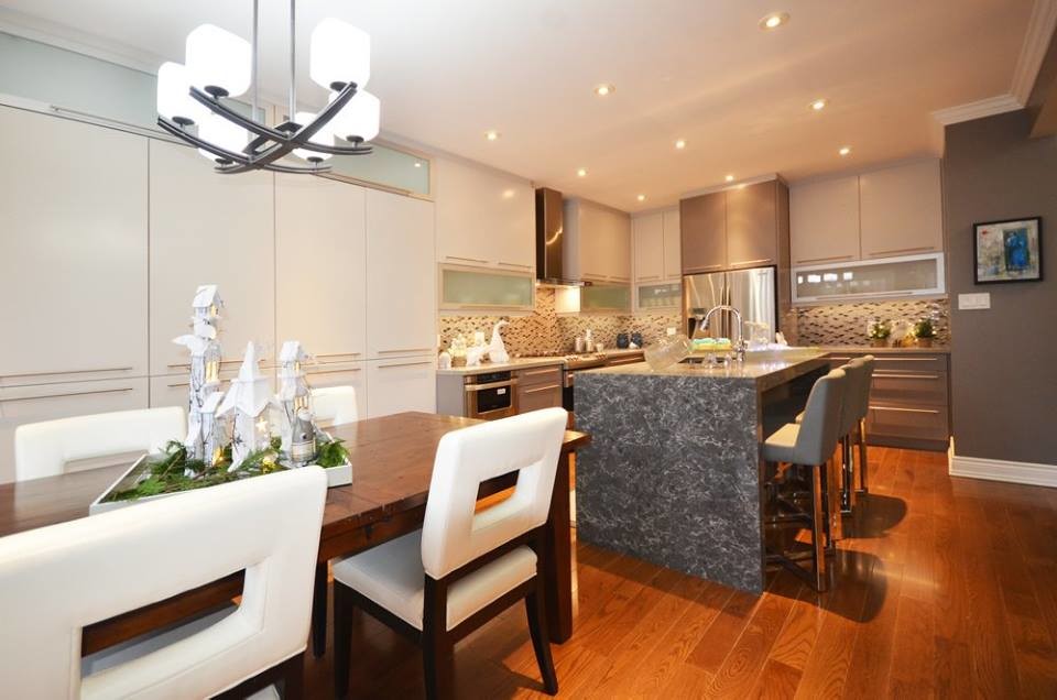 Inspiration for a large transitional l-shaped medium tone wood floor and brown floor eat-in kitchen remodel in Toronto with an undermount sink, flat-panel cabinets, white cabinets, beige backsplash, glass tile backsplash, stainless steel appliances and an island