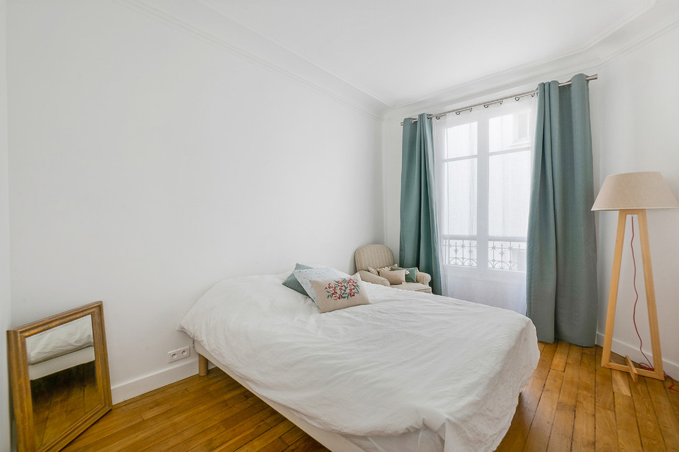 Photo of a mid-sized scandinavian master bedroom in Paris with white walls and light hardwood floors.