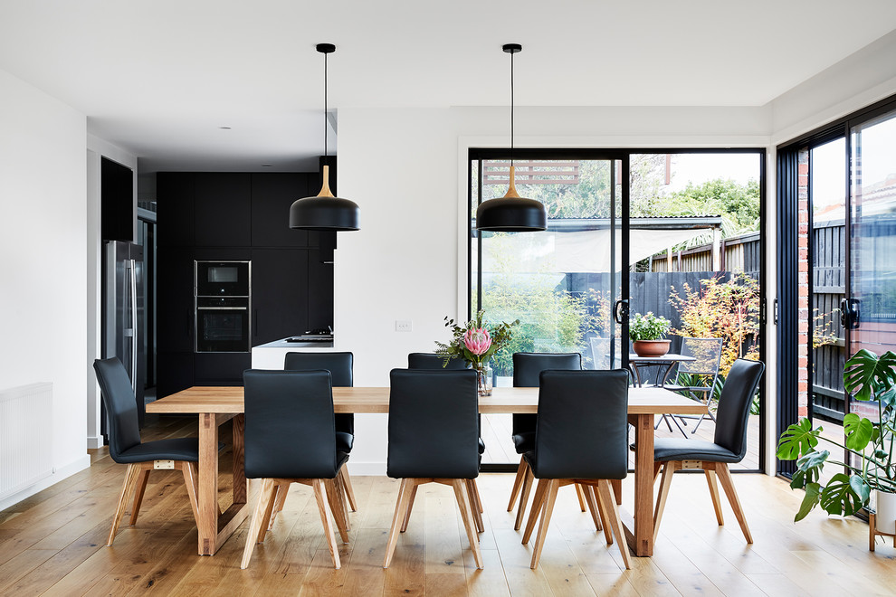 This is an example of a mid-sized contemporary kitchen/dining combo in Melbourne with white walls, medium hardwood floors and brown floor.