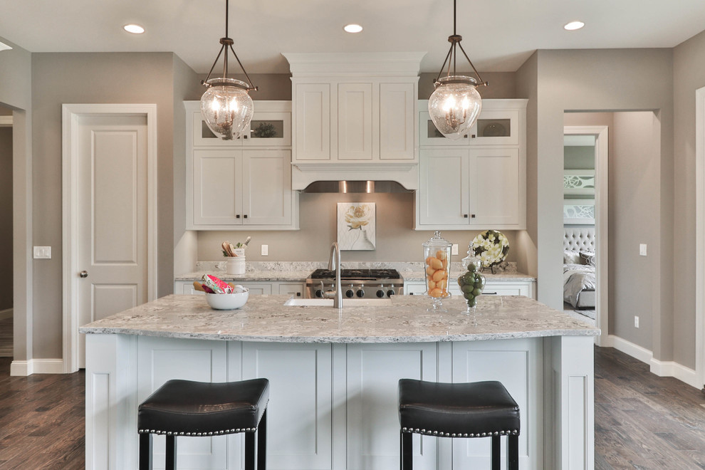 Open concept kitchen - mid-sized transitional l-shaped dark wood floor and brown floor open concept kitchen idea in St Louis with a farmhouse sink, shaker cabinets, white cabinets, granite countertops, gray backsplash, stainless steel appliances and an island