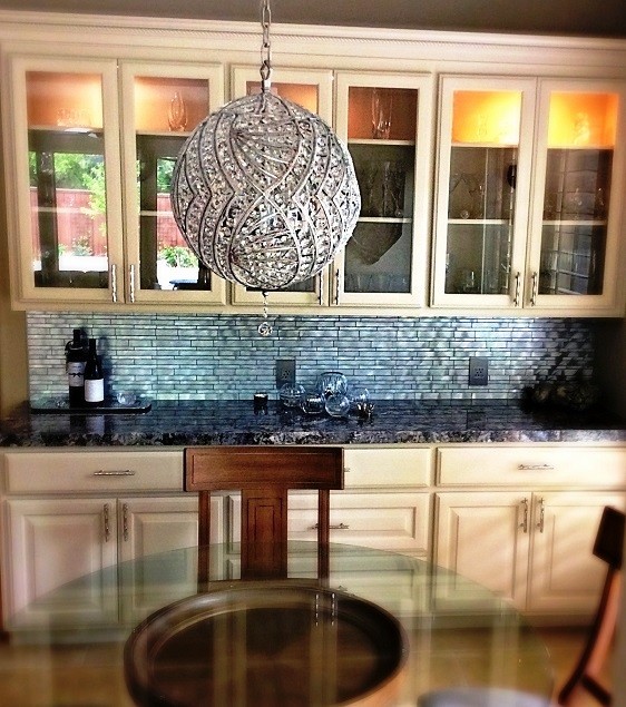 Mid-sized transitional l-shaped travertine floor eat-in kitchen photo in Houston with a farmhouse sink, raised-panel cabinets, white cabinets, granite countertops, metallic backsplash, metal backsplash, stainless steel appliances and an island