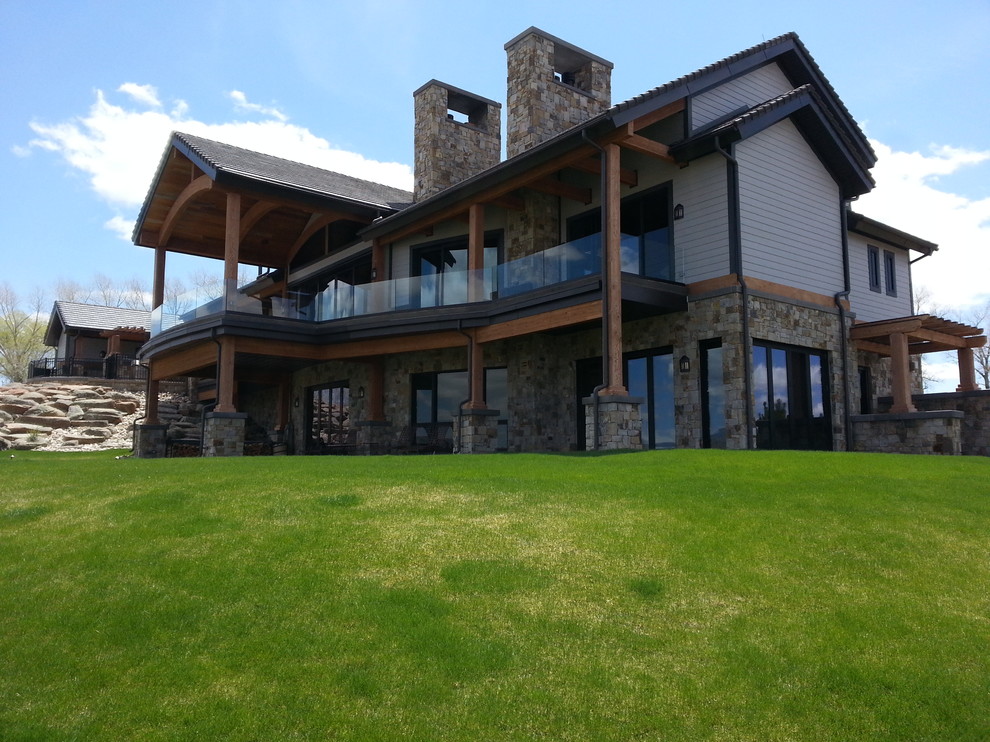 Design ideas for an expansive country two-storey white exterior in Denver with stone veneer.