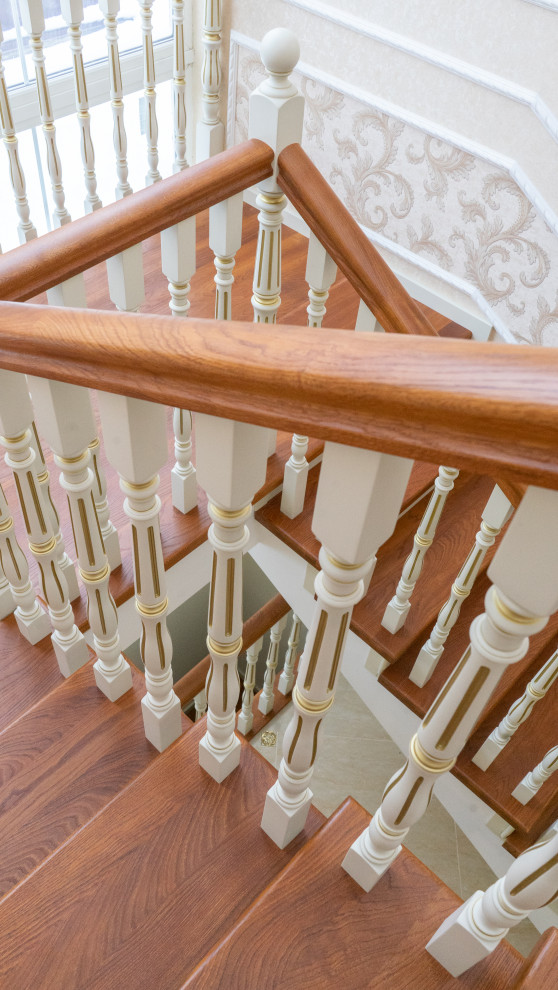Ejemplo de escalera en U clásica grande con escalones de madera, contrahuellas de madera, barandilla de madera y ladrillo