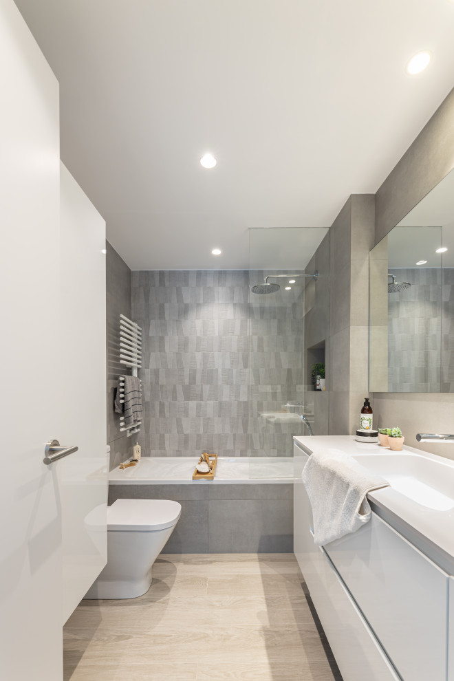 Inspiration för mellanstora moderna vitt en-suite badrum, med släta luckor, vita skåp, bänkskiva i kvarts, ett badkar i en alkov, en dusch/badkar-kombination, grå kakel, ett integrerad handfat och med dusch som är öppen