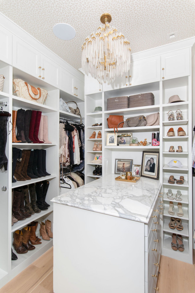 Design ideas for a mid-sized transitional walk-in wardrobe in Austin with shaker cabinets, white cabinets, light hardwood floors and wallpaper.