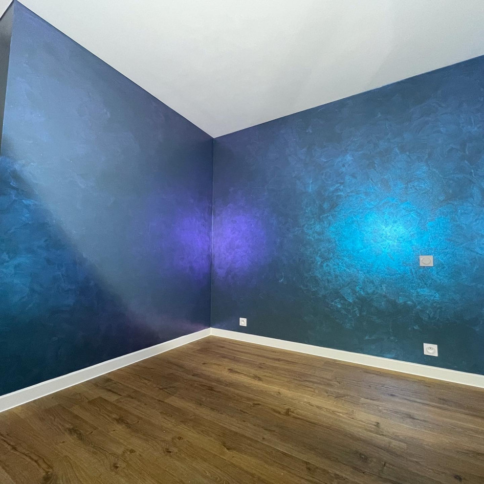 Inspiration pour une chambre d'amis minimaliste de taille moyenne avec un mur bleu, sol en stratifié, aucune cheminée, un sol marron et différents habillages de murs.
