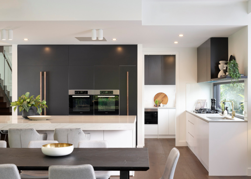 Inspiration for an expansive contemporary l-shaped open plan kitchen in Brisbane with black appliances and with island.