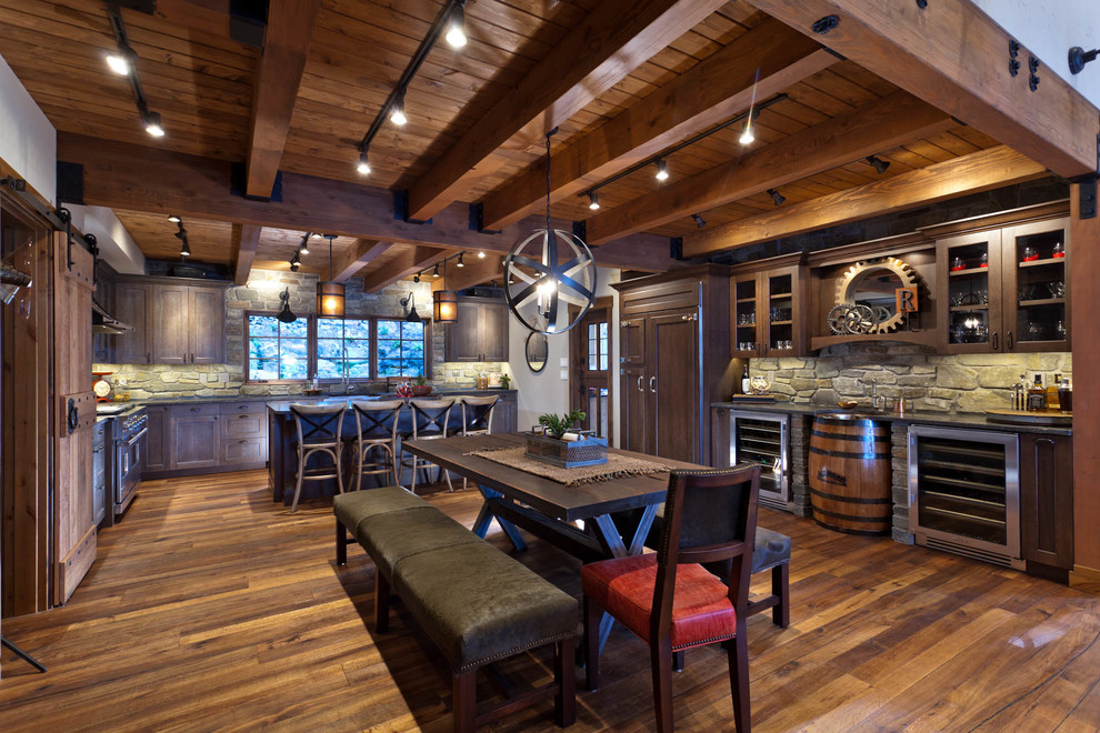Example of a mountain style kitchen design in Seattle with medium tone wood cabinets, limestone backsplash and stainless steel appliances