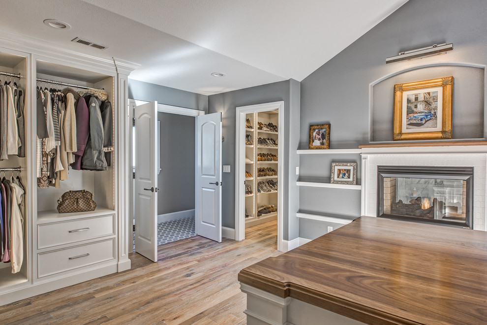 Photo of an expansive transitional gender-neutral dressing room in Denver with beaded inset cabinets, white cabinets and light hardwood floors.