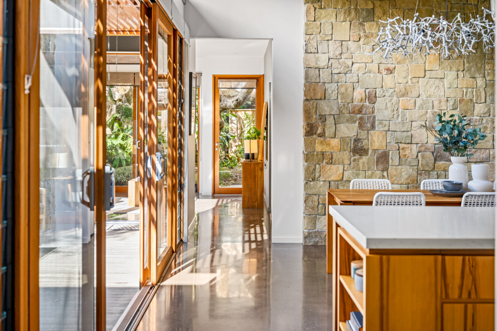 На фото: гостиная-столовая среднего размера в современном стиле с коричневыми стенами, бетонным полом, серым полом, балками на потолке и панелями на стенах
