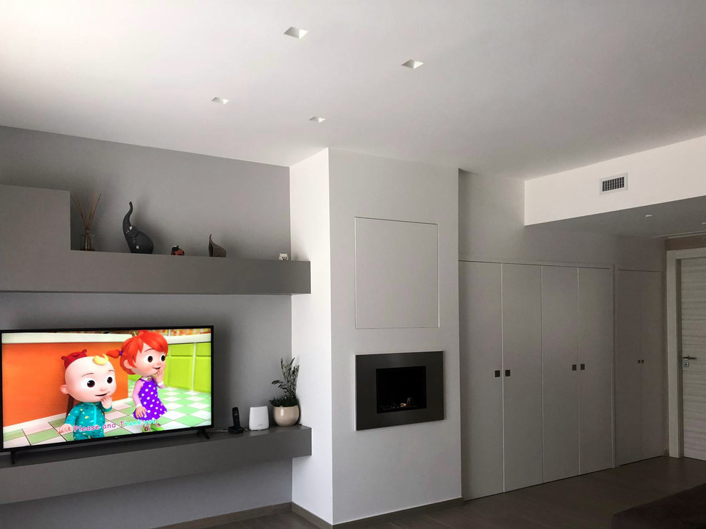 Small modern enclosed family room in Other with grey walls, porcelain floors, a hanging fireplace, a plaster fireplace surround, a built-in media wall and multi-coloured floor.