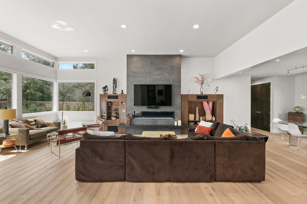 Mid-sized contemporary open concept living room in Denver with white walls, medium hardwood floors, a ribbon fireplace, a tile fireplace surround, a wall-mounted tv and brown floor.