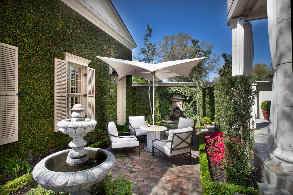 This is an example of a traditional courtyard patio in New Orleans with a vertical garden and brick pavers.