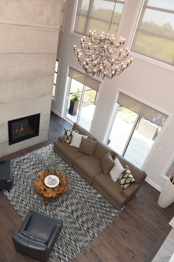 Large contemporary formal enclosed living room in Ottawa with grey walls, dark hardwood floors, a standard fireplace, a concrete fireplace surround, no tv and brown floor.