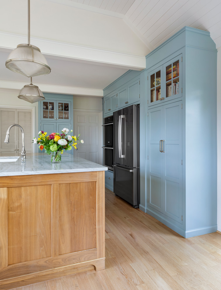 Foto på ett mellanstort vintage vit kök, med en rustik diskho, skåp i shakerstil, blå skåp, bänkskiva i kvartsit, vitt stänkskydd, stänkskydd i tunnelbanekakel, rostfria vitvaror, ljust trägolv och en köksö