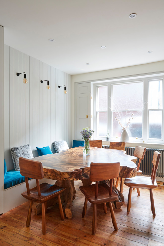 This is an example of a mid-sized beach style open plan dining in London with white walls, light hardwood floors and brown floor.