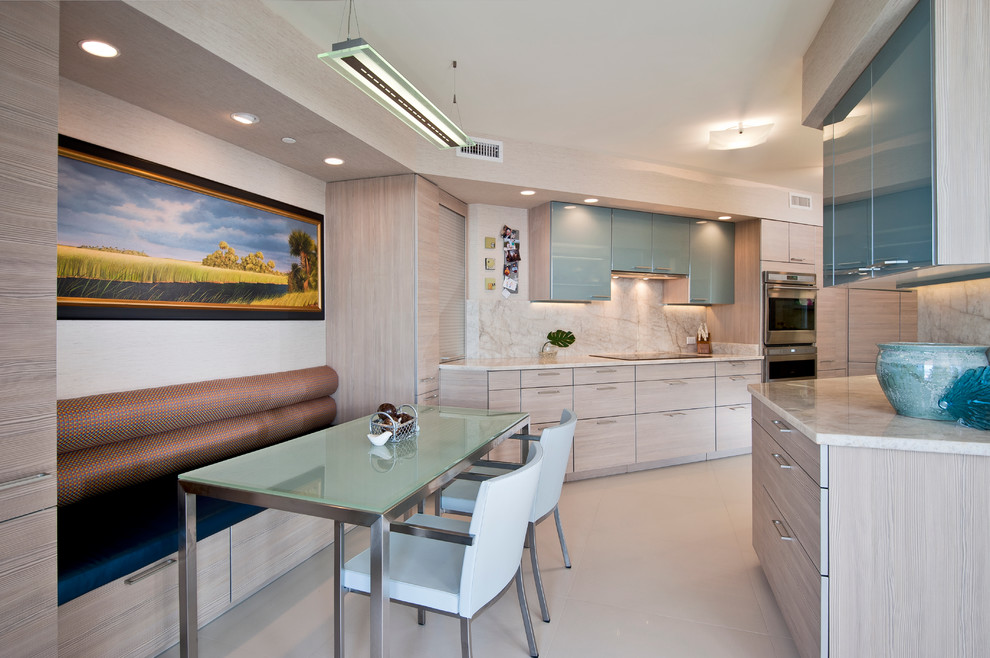 Contemporary galley separate kitchen in Miami with flat-panel cabinets, light wood cabinets, beige splashback, stone slab splashback, stainless steel appliances and marble benchtops.