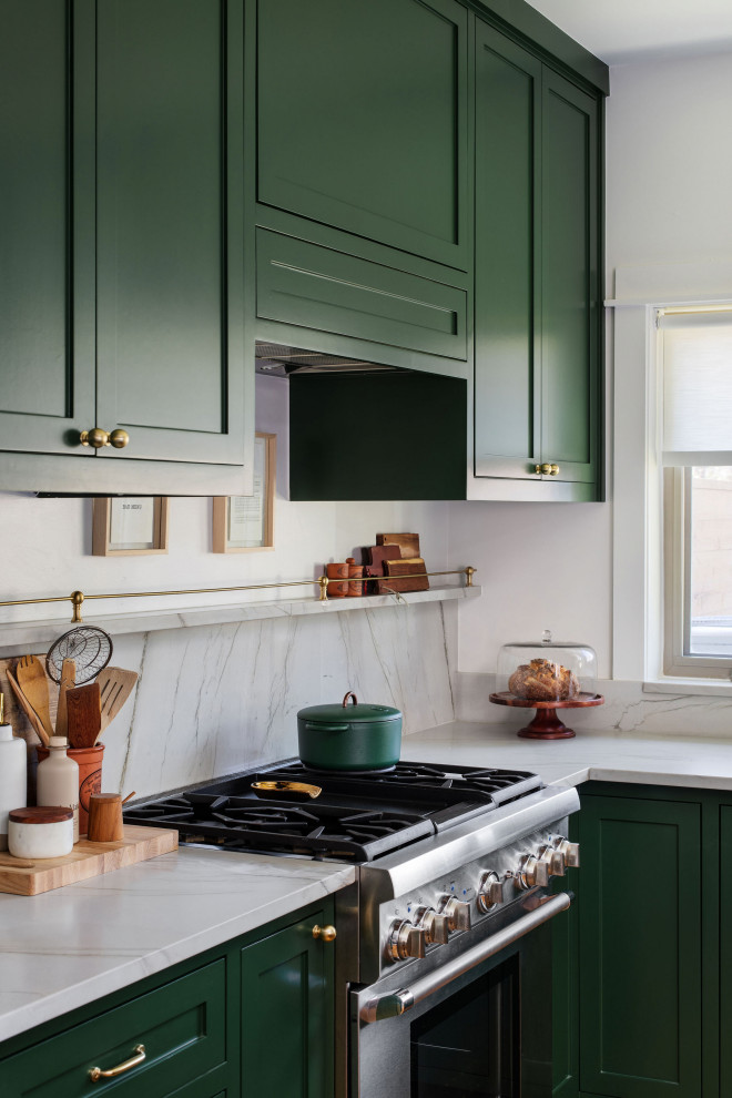 Example of a mid-sized transitional u-shaped medium tone wood floor and brown floor open concept kitchen design in Austin with an undermount sink, shaker cabinets, green cabinets, quartzite countertops, white backsplash, stone slab backsplash, stainless steel appliances, an island and white countertops