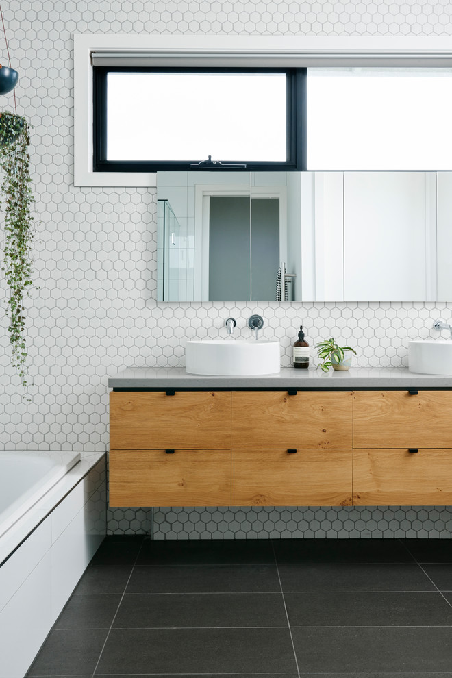 Photo of a contemporary master bathroom in Other with flat-panel cabinets, medium wood cabinets, a corner tub, white tile, ceramic tile, white walls, a vessel sink and concrete benchtops.