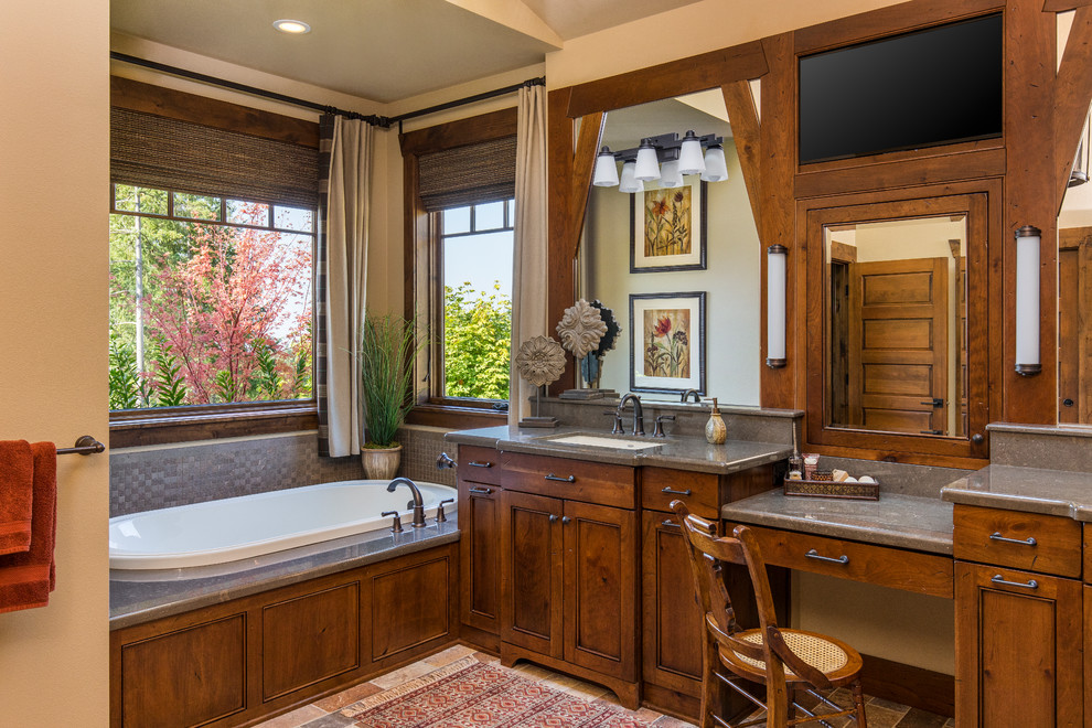 Mountain style brown floor drop-in bathtub photo in Portland with recessed-panel cabinets, dark wood cabinets, beige walls, an undermount sink and gray countertops