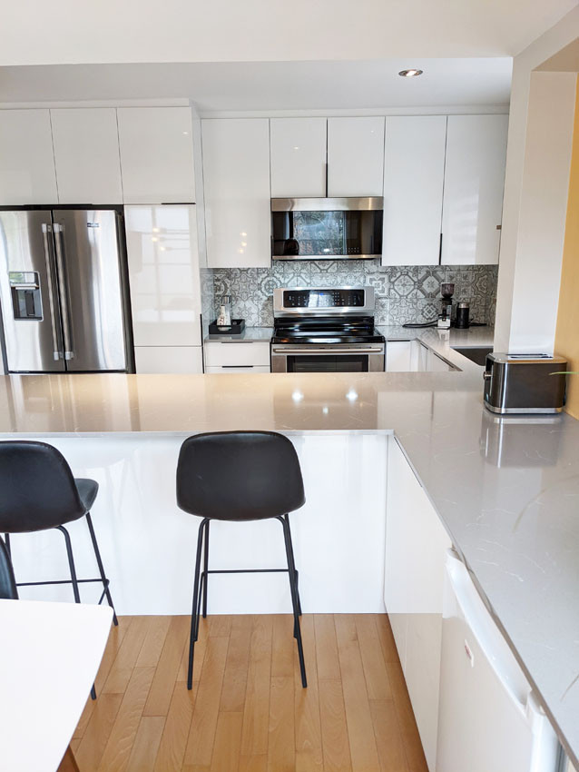 Mid-sized trendy galley vinyl floor and gray floor eat-in kitchen photo in Montreal with an undermount sink, flat-panel cabinets, white cabinets, quartz countertops, gray backsplash, cement tile backsplash, stainless steel appliances, a peninsula and gray countertops