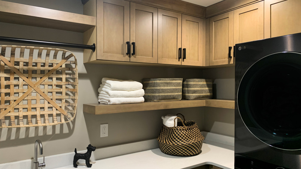 Dedicated laundry room - mid-sized transitional l-shaped ceramic tile and multicolored floor dedicated laundry room idea in Minneapolis with an undermount sink, shaker cabinets, medium tone wood cabinets, beige walls, a stacked washer/dryer and white countertops