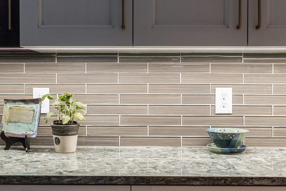 Mid-sized transitional galley medium tone wood floor open concept kitchen photo with a drop-in sink, flat-panel cabinets, white cabinets, granite countertops, glass tile backsplash, stainless steel appliances and an island