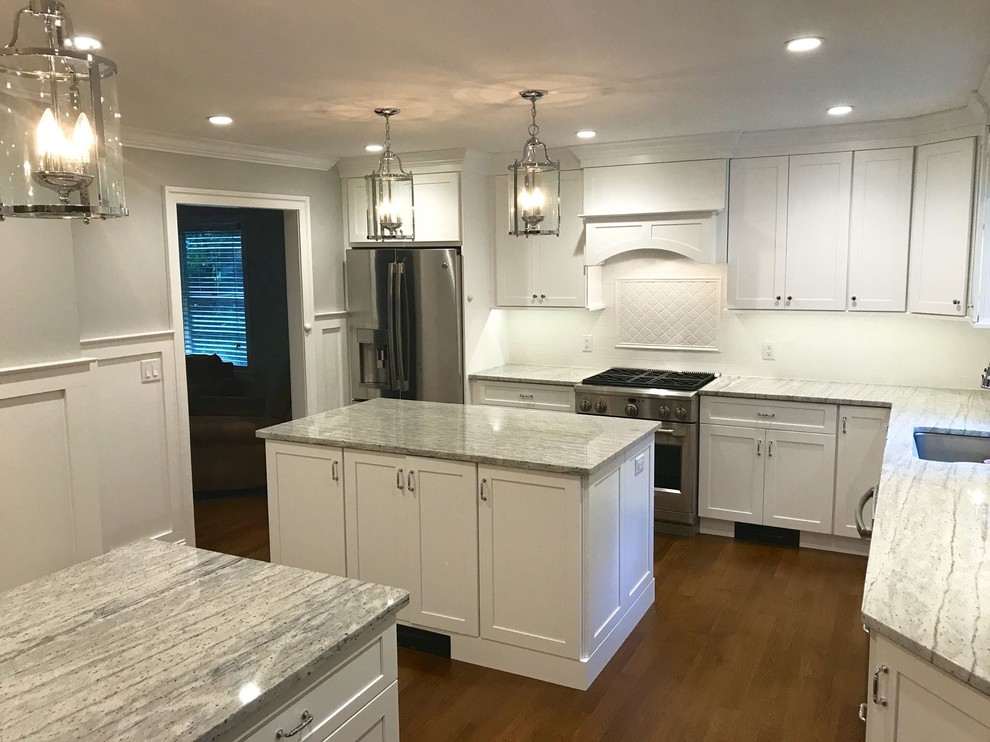 Enclosed kitchen - large transitional l-shaped dark wood floor and brown floor enclosed kitchen idea with an undermount sink, shaker cabinets, white cabinets, marble countertops, white backsplash, ceramic backsplash, stainless steel appliances and two islands