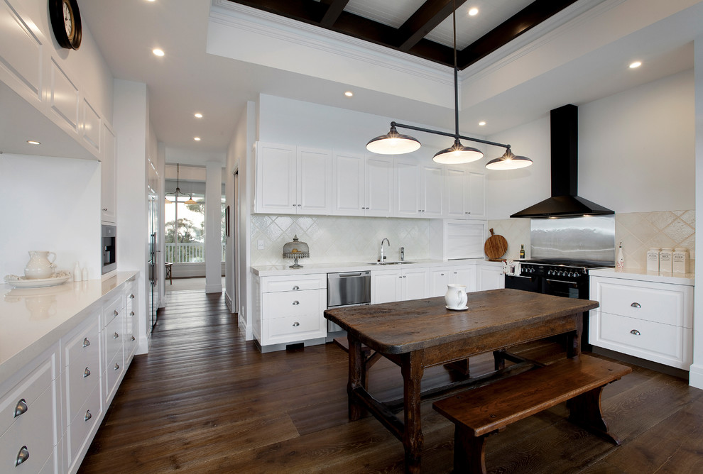 This is an example of a country u-shaped eat-in kitchen in Melbourne with raised-panel cabinets, white cabinets, white splashback, black appliances and dark hardwood floors.