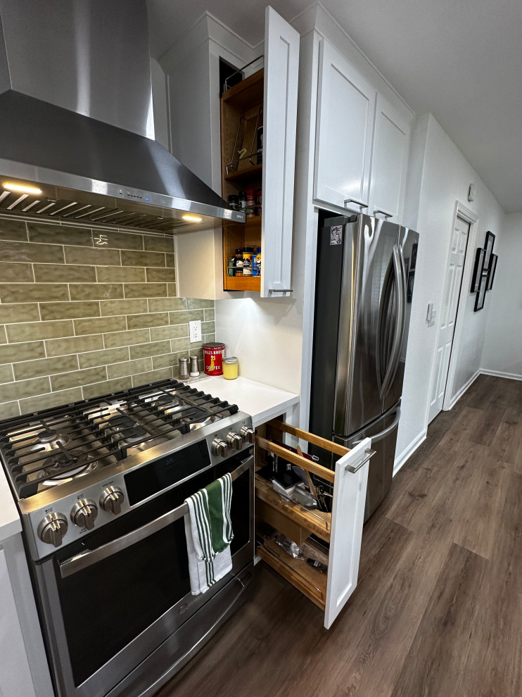 This is an example of a mid-sized transitional galley eat-in kitchen in Other with a single-bowl sink, shaker cabinets, white cabinets, quartz benchtops, green splashback, subway tile splashback, stainless steel appliances, a peninsula and white benchtop.