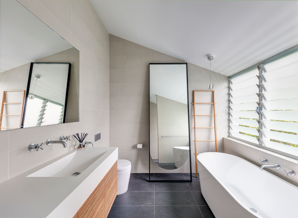 Inspiration for a contemporary master bathroom in Sydney with flat-panel cabinets, medium wood cabinets, a freestanding tub, a curbless shower, a one-piece toilet, beige tile, beige walls, an integrated sink, grey floor and an open shower.