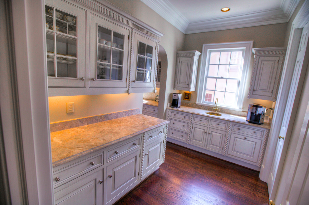 Kitchen pantry - mid-sized transitional l-shaped medium tone wood floor kitchen pantry idea in Charlotte with an undermount sink, raised-panel cabinets, white cabinets, marble countertops, multicolored backsplash, stone slab backsplash, stainless steel appliances and an island