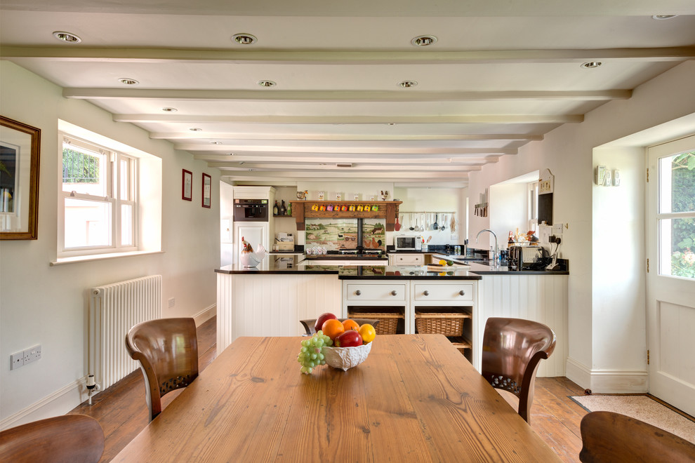 Photo of a large traditional u-shaped eat-in kitchen in Devon with shaker cabinets, distressed cabinets, granite benchtops, multi-coloured splashback, ceramic splashback, coloured appliances and medium hardwood floors.