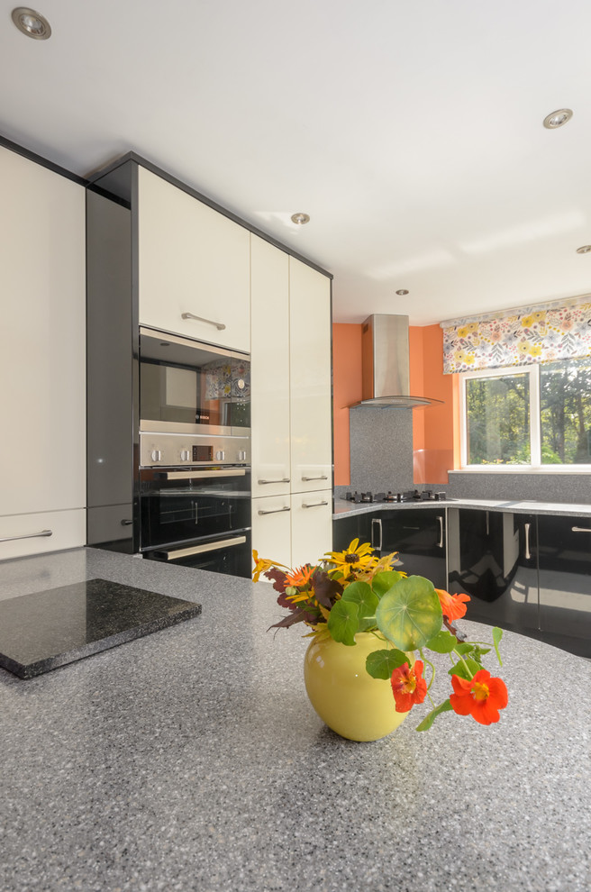 Mid-sized modern kitchen in Other with black cabinets, solid surface benchtops and grey splashback.