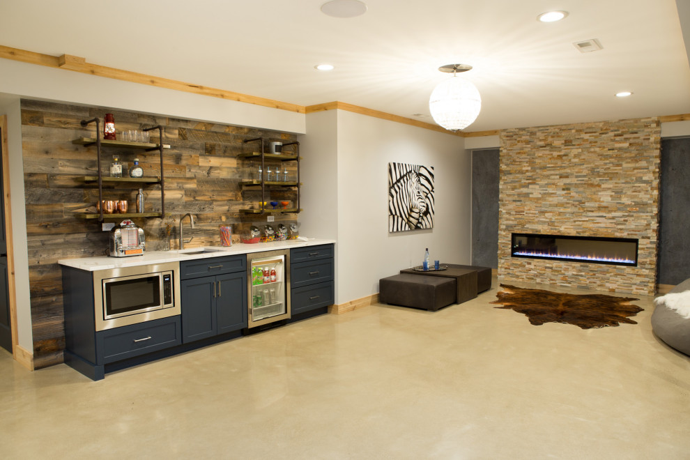 This is an example of an expansive transitional look-out basement in Chicago with white walls, concrete floors, a ribbon fireplace, a stone fireplace surround and grey floor.