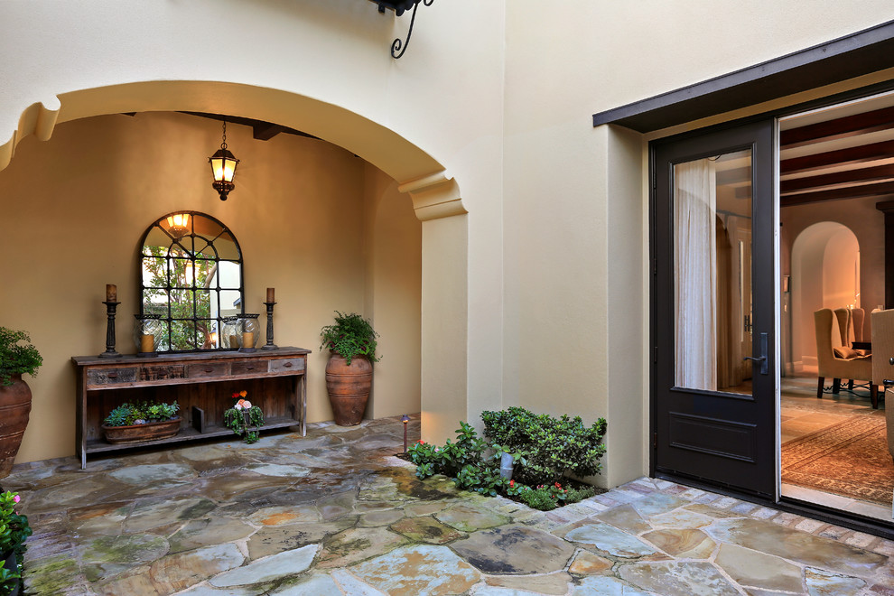 This is an example of a large mediterranean two-storey stucco beige house exterior in Orange County with a tile roof.