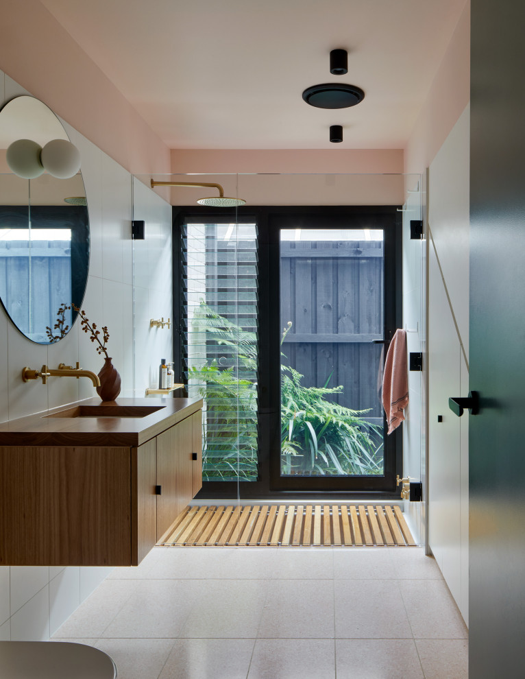 This is an example of a small midcentury master bathroom in Melbourne with recessed-panel cabinets, light wood cabinets, an undermount tub, an open shower, a one-piece toilet, pink tile, ceramic tile, pink walls, terrazzo floors, an undermount sink, wood benchtops, pink floor, an open shower, brown benchtops, a single vanity and a built-in vanity.