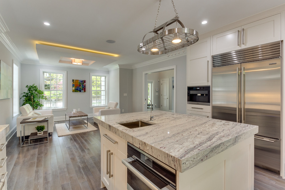 Large transitional l-shaped medium tone wood floor open concept kitchen photo in DC Metro with a double-bowl sink, shaker cabinets, white cabinets, marble countertops, white backsplash, porcelain backsplash, stainless steel appliances and an island