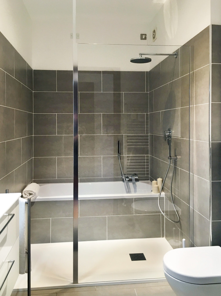 This is an example of a mid-sized modern bathroom in Turin with white cabinets, a drop-in tub, a shower/bathtub combo, a bidet, gray tile, ceramic tile, white walls, cement tiles, a drop-in sink, laminate benchtops, white floor, an open shower, white benchtops, a single vanity and a floating vanity.