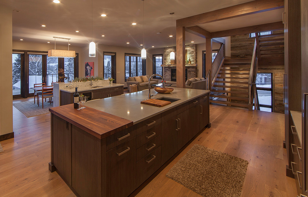 Photo of a large contemporary l-shaped open plan kitchen in Denver with a single-bowl sink, flat-panel cabinets, medium wood cabinets, granite benchtops, white splashback, stone tile splashback, stainless steel appliances, light hardwood floors and multiple islands.