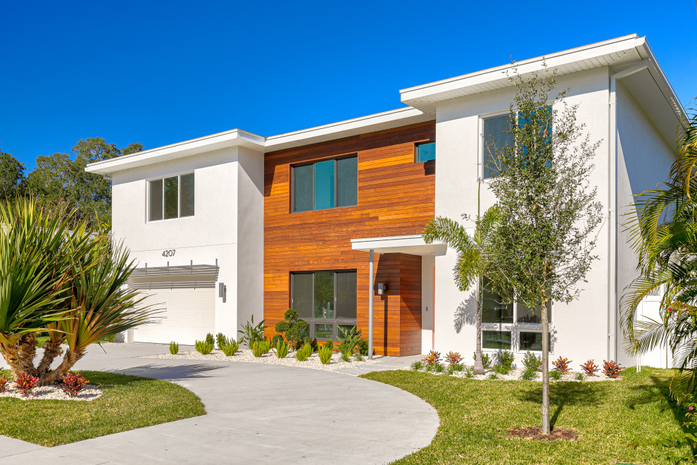 Large modern two-storey stucco white house exterior in Tampa with a shingle roof and a brown roof.