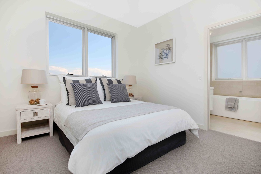 This is an example of a beach style bedroom in Sydney with white walls, carpet and no fireplace.