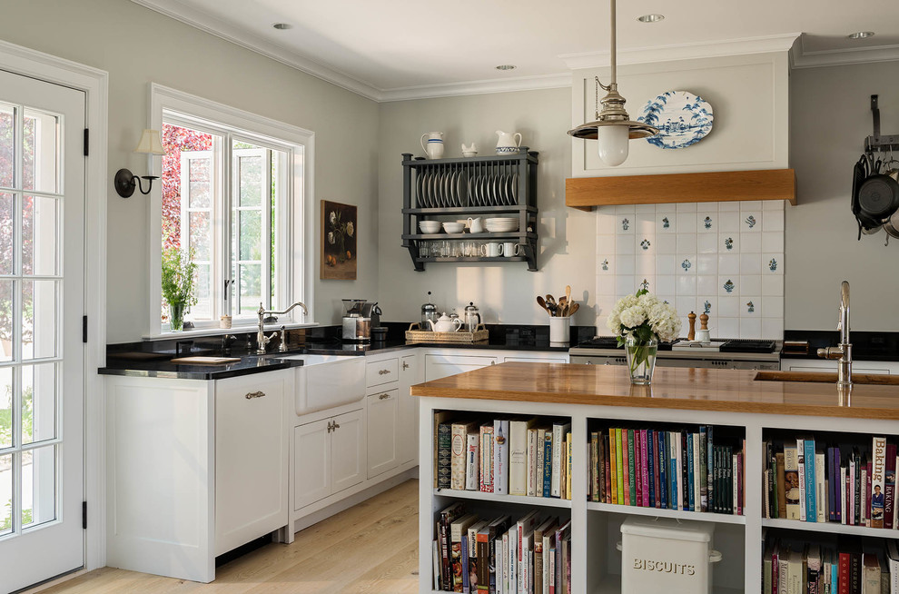 Inspiration for a mid-sized country u-shaped open plan kitchen in Bridgeport with a farmhouse sink, shaker cabinets, white cabinets, granite benchtops, white splashback, porcelain splashback, stainless steel appliances, light hardwood floors, with island and beige floor.