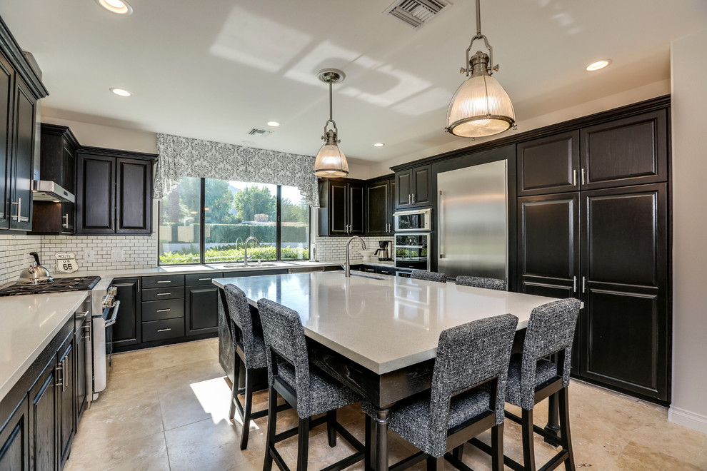 Eat-in kitchen - mid-sized transitional u-shaped travertine floor and brown floor eat-in kitchen idea with an undermount sink, raised-panel cabinets, black cabinets, quartz countertops, white backsplash, subway tile backsplash, stainless steel appliances, an island and gray countertops