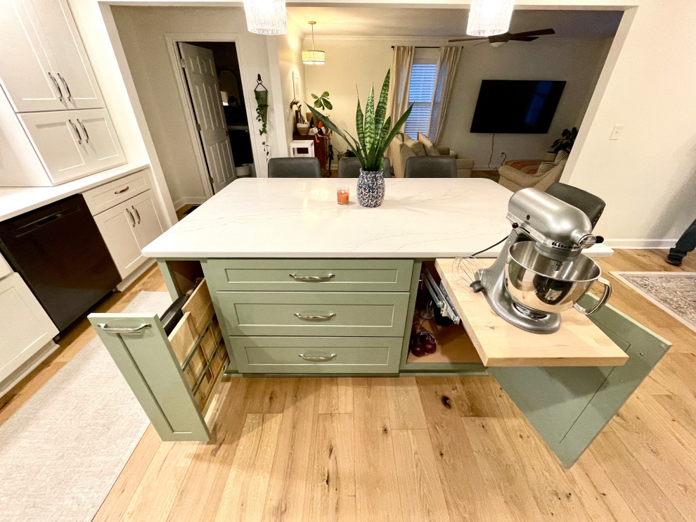 Example of a transitional l-shaped light wood floor and beige floor eat-in kitchen design with a farmhouse sink, shaker cabinets, white cabinets, quartz countertops, white backsplash, quartz backsplash, black appliances, an island and white countertops
