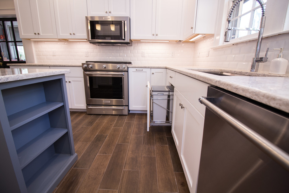 Small u-shaped ceramic tile eat-in kitchen photo with an undermount sink, shaker cabinets, white cabinets, quartz countertops, white backsplash, subway tile backsplash, stainless steel appliances, an island and white countertops