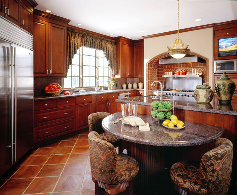 Inspiration for a large traditional l-shaped eat-in kitchen in Detroit with an undermount sink, raised-panel cabinets, brown cabinets, granite benchtops, brown splashback, terra-cotta splashback, stainless steel appliances, terra-cotta floors, with island, brown floor and grey benchtop.