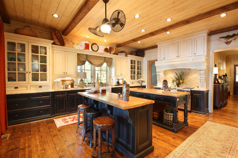 Design ideas for a country l-shaped separate kitchen in Atlanta with recessed-panel cabinets, wood benchtops, beige splashback, stone tile splashback, a farmhouse sink, stainless steel appliances, medium hardwood floors, multiple islands, brown floor and beige benchtop.