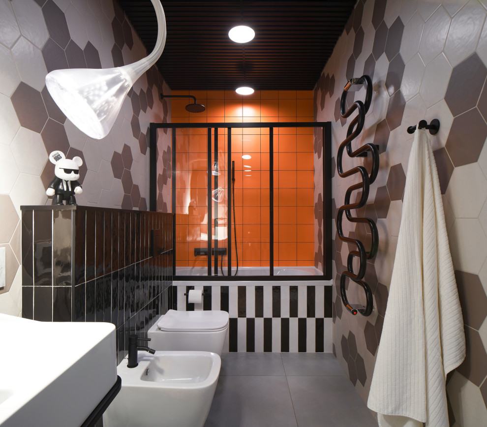 This is an example of a medium sized contemporary grey and white family bathroom in Yekaterinburg with flat-panel cabinets, black cabinets, an alcove bath, a shower/bath combination, a wall mounted toilet, multi-coloured tiles, ceramic tiles, multi-coloured walls, ceramic flooring, a pedestal sink, tiled worktops, grey floors, a sliding door, black worktops, feature lighting, a single sink, a freestanding vanity unit, a wood ceiling and panelled walls.