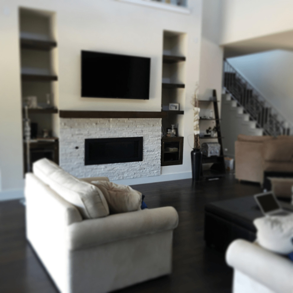 This is an example of a contemporary family room in Austin with white walls, dark hardwood floors, a standard fireplace, a brick fireplace surround, a wall-mounted tv and brown floor.